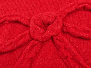 Macro detail of red cable-knit texture with a decorative 3D oversized bow knot
