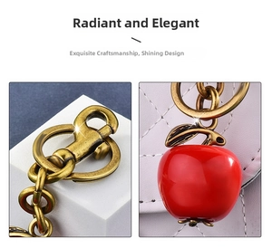 Close-up of red apple charm with vintage gold metal clasp and textured chain detail
