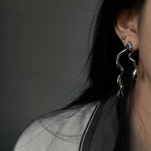 Close-up of silver snake drop earrings with liquid metal aesthetic on a model