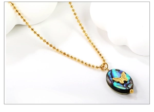 Close-up of golden butterfly pendant with colorful abalone shell on a bead chain