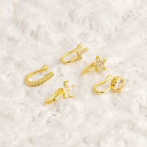 Macro detail of gold U-shaped nose clips with micro-inlaid zircons on white texture