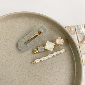Detailed view of three pearl and glitter hair clips on a decorative ceramic plate