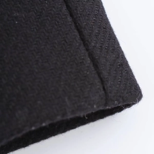 Close-up of black herringbone wool fabric texture and stitching on the long coat