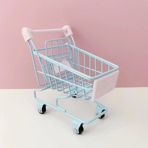 Detailed macro view of a light blue mini metal shopping basket on a soft pink background