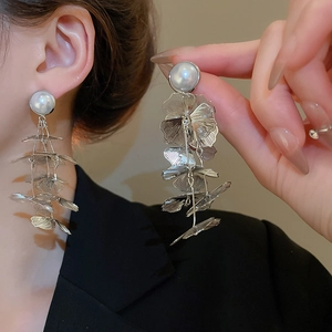 Close-up of silver hollow flower tassel earrings featuring layered petals and white pearls