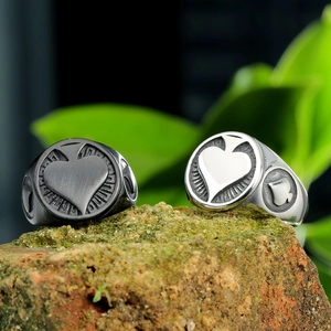 Macro shot of black and silver spade heart rings placed on natural mossy rock
