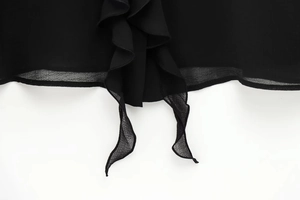 Detail der zweilagigen gewellten Plissee-Saumkante an einer schwarzen Chiffonbluse