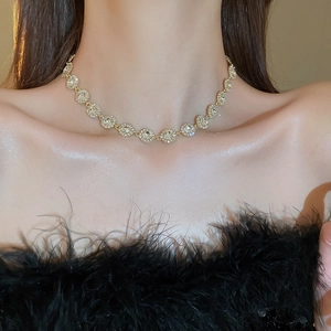 Collier ras du cou doré luxueux avec cristaux étincelants sur fond de plumes noires