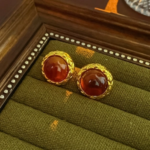 Macro shot of vintage round gold earrings with amber resin and matelassé metal patterns