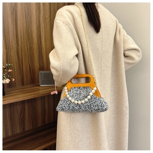 Detail of tweed evening bag with wooden handle and faux pearl chain decoration