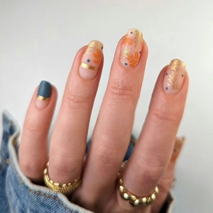 Short press-on nails with autumn maple leaf designs and minimalist geometric patterns
