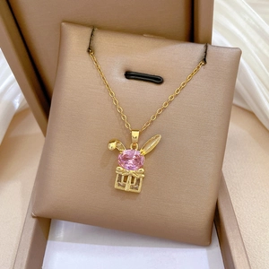 Detail of gold rabbit pendant with pink gemstones and gift box on a silk display
