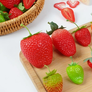 Realistic artificial strawberries in various ripeness on bamboo board for display