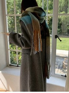 Detail of colorful plaid scarf with tassels paired with a thick grey winter coat