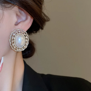 Close-up of vintage gold stud earring featuring a large faux pearl with double crystal halo