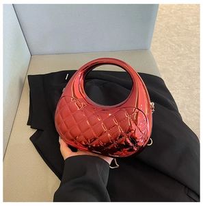 Detail of glossy metallic red handbag featuring diamond quilted pattern and round handle