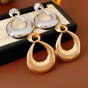 Detail of minimalist gold and silver teardrop earrings in a black display gift box