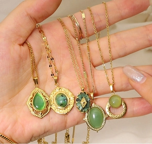 Detailed view of bohemian gold necklaces with oval and teardrop green stone pendants