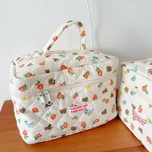 Detailed view of quilted floral bear makeup bag with sturdy handle and secure zipper closure
