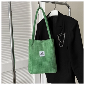 Detail shot of green corduroy tote bag texture with minimalist white label patch