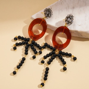 Gros plan de boucles d'oreilles en résine avec glands perlés noirs et cristaux gris