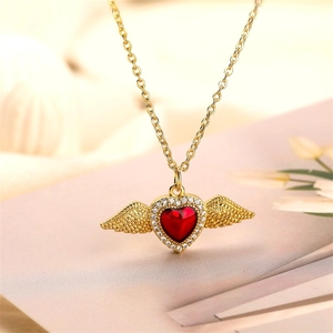 Dettaglio macro della collana placcata oro con cuore in zircone rosso e ali d'angelo
