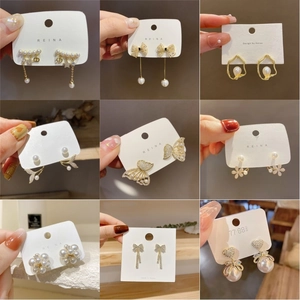 Dettaglio di eleganti orecchini dorati con perle, zirconi e design a farfalla