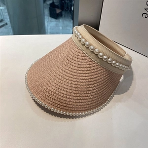 Detail of pink woven straw sun visor hat with elegant white pearl beaded embellishments