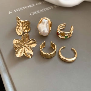 Detail of 6-piece gold ring set featuring baroque pearl, flower design, and hammered metal texture
