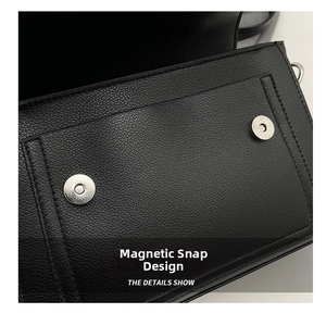 Detail of black pebbled leather handbag featuring a secure double magnetic snap closure