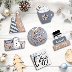 Flat lay of gray and white wooden snowman tray ornaments with festive pine decorations