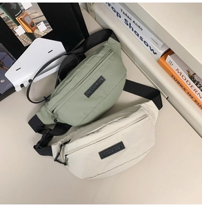 Detail view of grey-green and cream nylon chest bags with adjustable straps and buckles