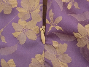 Close-up of purple jacquard fabric with gold floral patterns and an invisible zipper detail