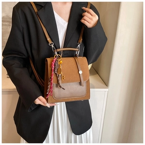 Detalle de bolso vintage de ante marrón con pañuelo de seda y colgante de raqueta
