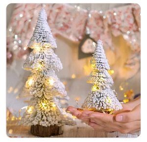 Detail of two flocked tabletop Christmas trees with LED lights and wooden bases