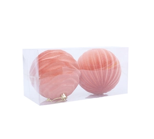 Detail of two pink velvet Christmas balls with textured patterns in a clear plastic box