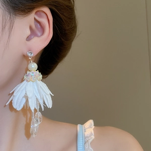 Detail of white fabric flower tassel earrings with pearls and crystal beads on a model