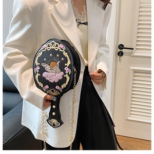 Close-up of baroque embroidery crossbody bag with angel motifs and pearl handle