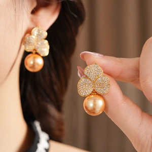 Detail of gold plated flower earrings with zircon pavé and large gold pearl drop