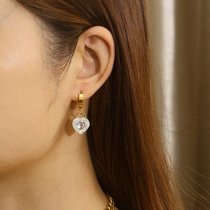 Close-up of heart-shaped gold earring with sparkling zircons worn by a model