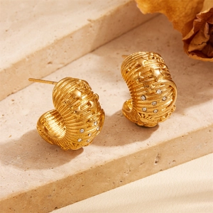 Detail of gold C-shaped earrings with celestial sun and moon motifs and cubic zirconia