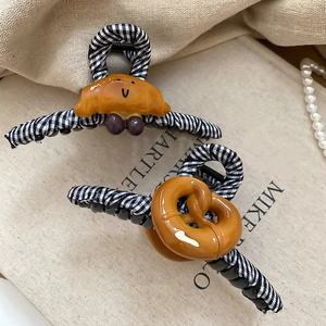 Détail de la pince à cheveux à carreaux avec accessoires mignons croissant et bretzel