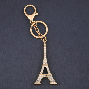 Porte-clés Tour Eiffel doré avec strass blancs et fermoir mousqueton sur fond sombre