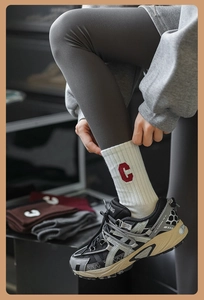 Gros plan de chaussettes blanches côtelées avec broderie lettre C rouge et baskets grises