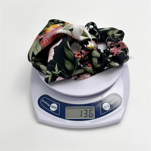 Weight measurement of black floral satin scrunchie showing 13.6g on a digital scale