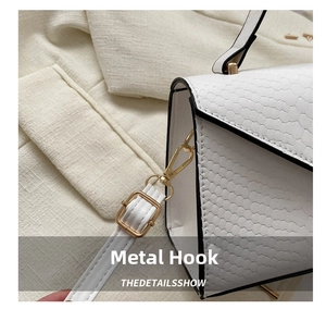 Close-up of golden metal hook on white crocodile texture crossbody bag with strap