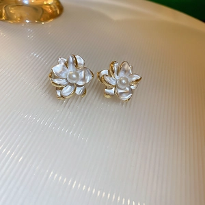 Close-up of elegant flower stud earrings with white petals, gold edges and center pearl