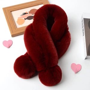 Close-up of soft red faux rabbit fur scarf featuring fluffy pom-pom detail on white table