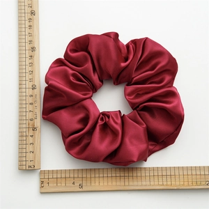 Macro shot of large burgundy satin scrunchie showing silky texture and 16cm diameter size