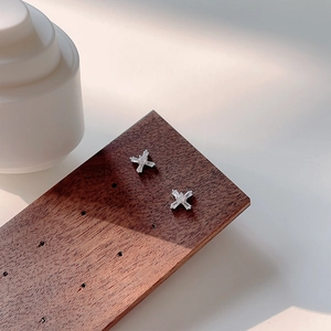 Minimalist 925 silver cross stud earrings with rectangular zircon stones on a wooden stand